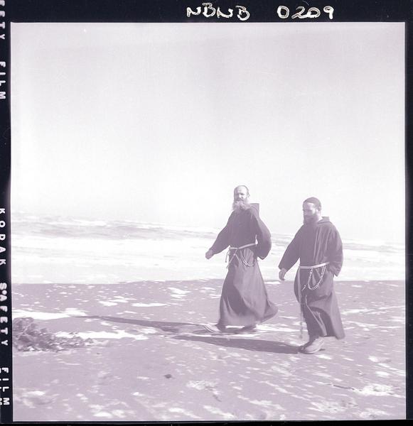 [Dos religiosos de la Orden Capuchinos, pasean por la orilla de la playa]