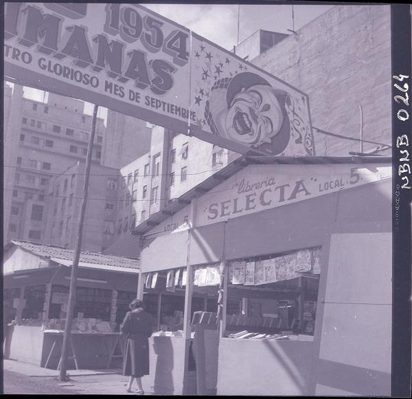 [Letrero que anuncia el Circo Las Aguilas Humanas 1954, y librerias de viejo instaladas en la calle]
