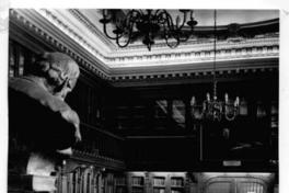 [Biblioteca Nacional. Sala de lectura de la Biblioteca Americana de Diego Barros Arana, se divisa estanterías, mesa rectangular y parte del busto de don Diego Barros Arana]
