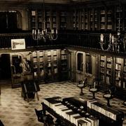[Vista interior de la Biblioteca Americana Barros Arana, Sala Medina, Biblioteca Nacional: espacio revestido en madera de nogal, Anaqueles con puerta de vidrio, parquet de maderas nobles, lámparas de techo en bronce, de 8 brazos con bombillas como velas, balconada en el segundo piso, busto de Barros Arana]