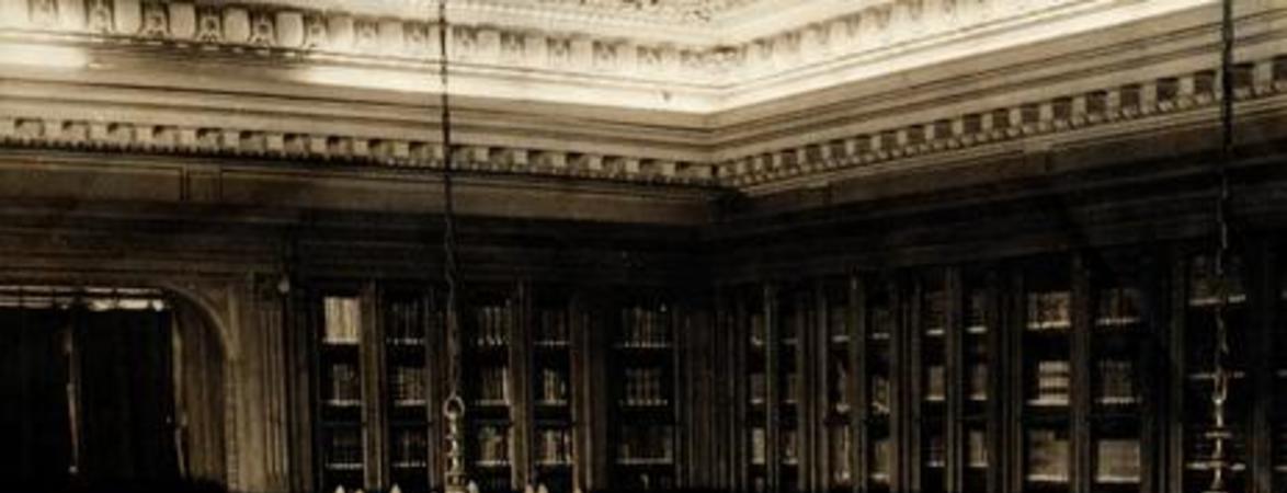 [Vista interior de la Biblioteca Americana Barros Arana, Sala Medina, Biblioteca Nacional: espacio revestido en madera de nogal, Anaqueles con puerta de vidrio, parquet de maderas nobles, lámparas de techo en bronce, de 8 brazos con bombillas como velas, balconada en el segundo piso, busto de Barros Arana]