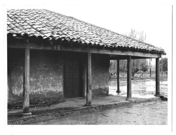 [Portal de una casa de adobe de campo, en un día de lluvia]