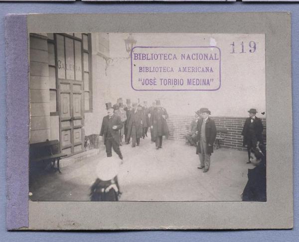 [Hombres en tenida formal entrando a un edificio]