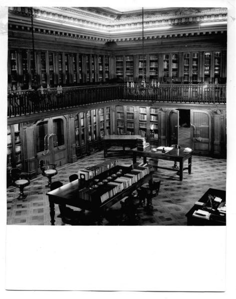 [Biblioteca Nacional. Sala de lectura de la Biblioteca Americana de Diego Barros Arana, se divisan unos escritorios y una mesa rectangular con libros]