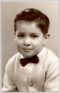 [Niño posando con una camisa blanca, corbatín oscuro y chaleco con botones de color claro]