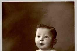 [Niñito rubio de ojos azules, con traje de hilo, zapatos y soquetes blancos sentado sobre un felpudo]