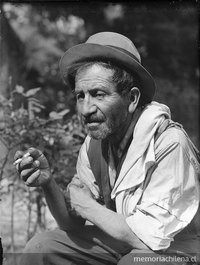 Hombre anciano con sombrero y camisa blanca fumando