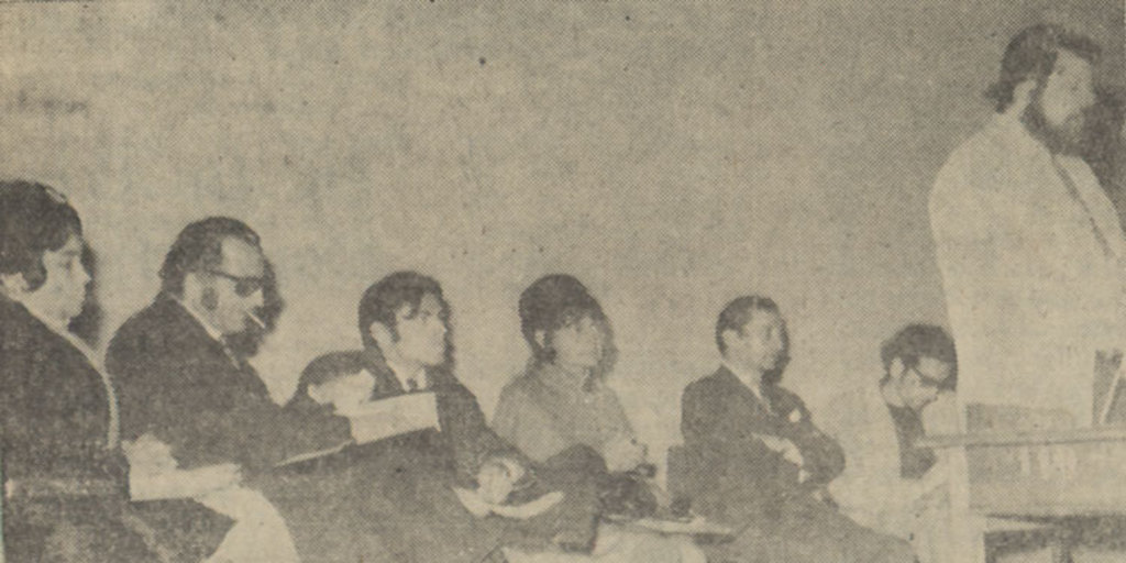 Oliver Welden de pie leyendo y Alicia Galaz sentada junto a grupo de escritores