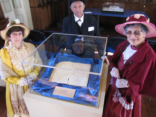 Libro Patrimonial en vitrina junto a participantes