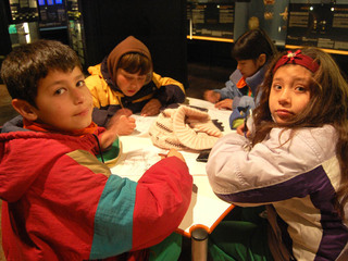 Niños y niñas coloreando ilustraciones en el museo