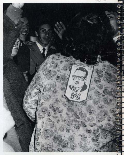 [Una señora portando en su espalda una fotografía del candidato Salvador Allende