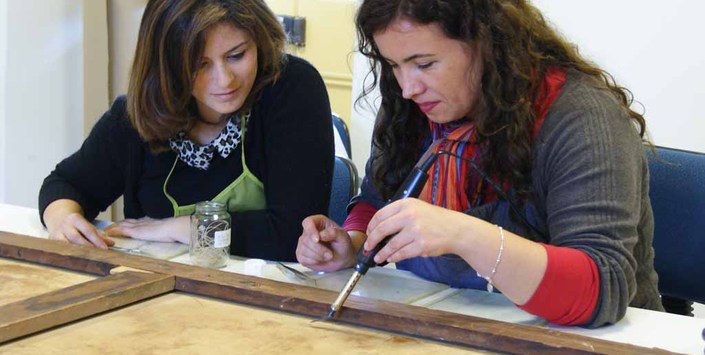 Pasante en investigación e intervención de pinturas de caballete junto a su tutora. Fotografía G. Reveco