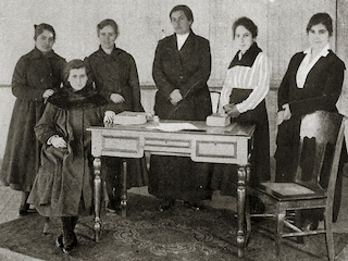 Laura Rodig (sentada) junto al resto de integrantes del cuerpo docente del Liceo de Niñas Punta Arenas. Álbum del Territorio de Magallanes. Carlos Foresti. 1920. Colección Museo Regional de Magallanes.
